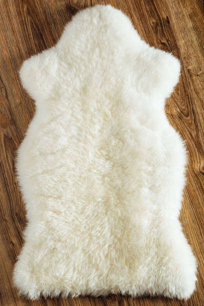 istock sheepskin carpet on wooden background 898537870