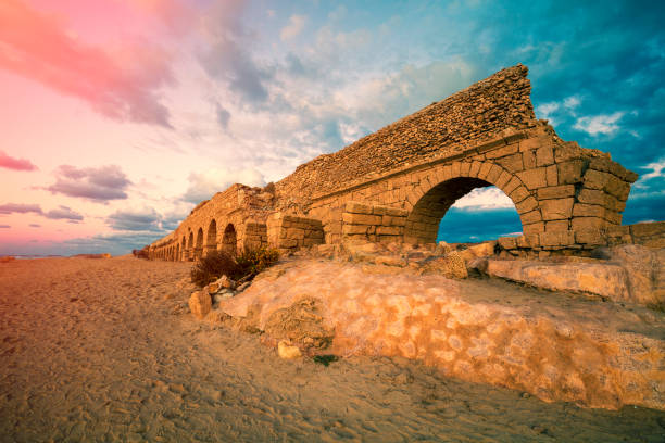 alten aquädukt am strand in caesarea, israel - caesarea maritima stock-fotos und bilder