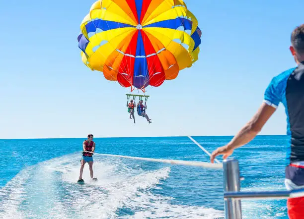 Happy couple Parasailing in Dominicana beach in summer. Couple under parachute hanging mid air. Positive human emotions, feelings, family. Young man glides on water skiing on the waves.Healthy lifestyle.