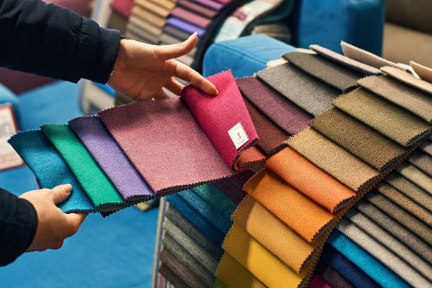 Choosing a fabric color in a store Young woman is making her decision while choosing a color of a fabric from a huge variety in a shop textile industry stock pictures, royalty-free photos & images