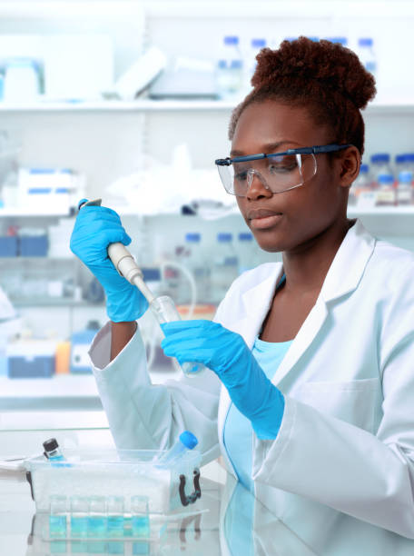 African-american scientist working in laboratory African-american scientist or graduate student in lab coat and protective wear works in modernl laboratory pipette photos stock pictures, royalty-free photos & images