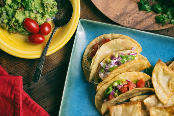 istock Overhead shot of several fresh tacos with cilantro on a square blue plate. 898578564