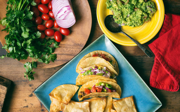 istock Overhead shot of several fresh tacos with cilantro on a square blue plate. 898578570