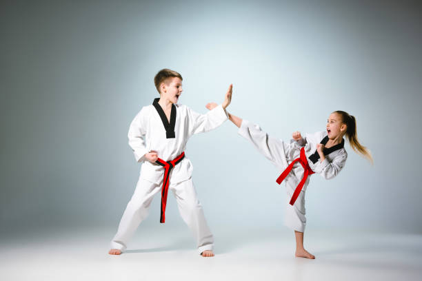 The studio shot of group of kids training karate martial arts The studio shot of group of kids training karate martial arts on gray backlground defending sport stock pictures, royalty-free photos & images