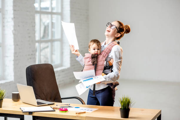 Businesswoman with her baby son working with documents at the office Multitasking businesswoman holding a pile of paper documents with her baby son standing at the office child laughing hysterically stock pictures, royalty-free photos & images