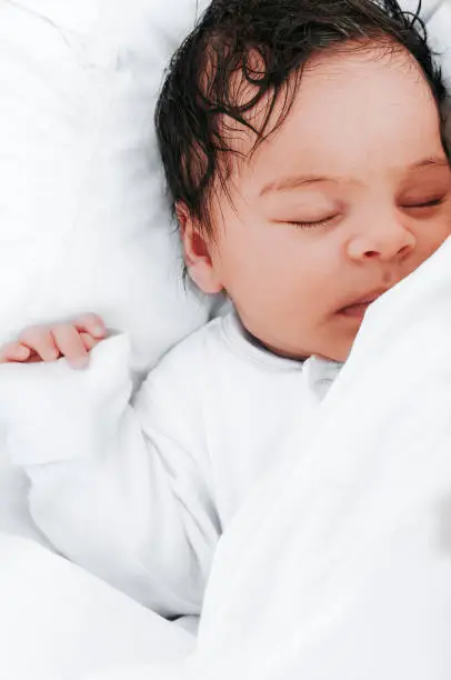 Stock photo of a sleeping one month old baby girl in her baby cot.