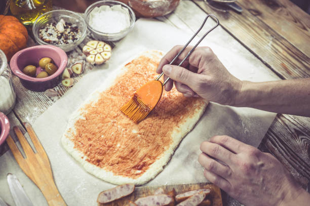 female hand sprinkles cheese on pizza. the woman makes home-made pizza. home-made pastries. mediterranean traditional cuisine. selective focus. easy toning - pizza sauces chef making imagens e fotografias de stock