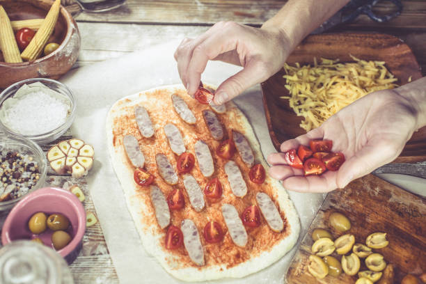 female hand sprinkles cheese on pizza. the woman makes home-made pizza. home-made pastries. mediterranean traditional cuisine. selective focus. easy toning - pizza sauces chef making imagens e fotografias de stock