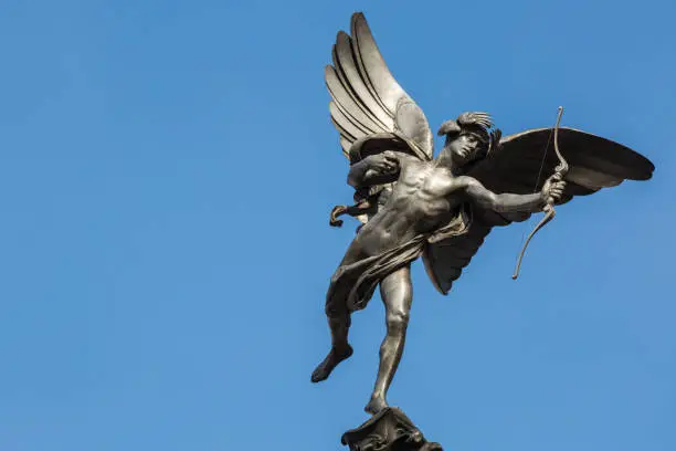 Famous statue of Eros, Amor, Cupid at Piccadilly Circus in London, UK, on blue clear sky