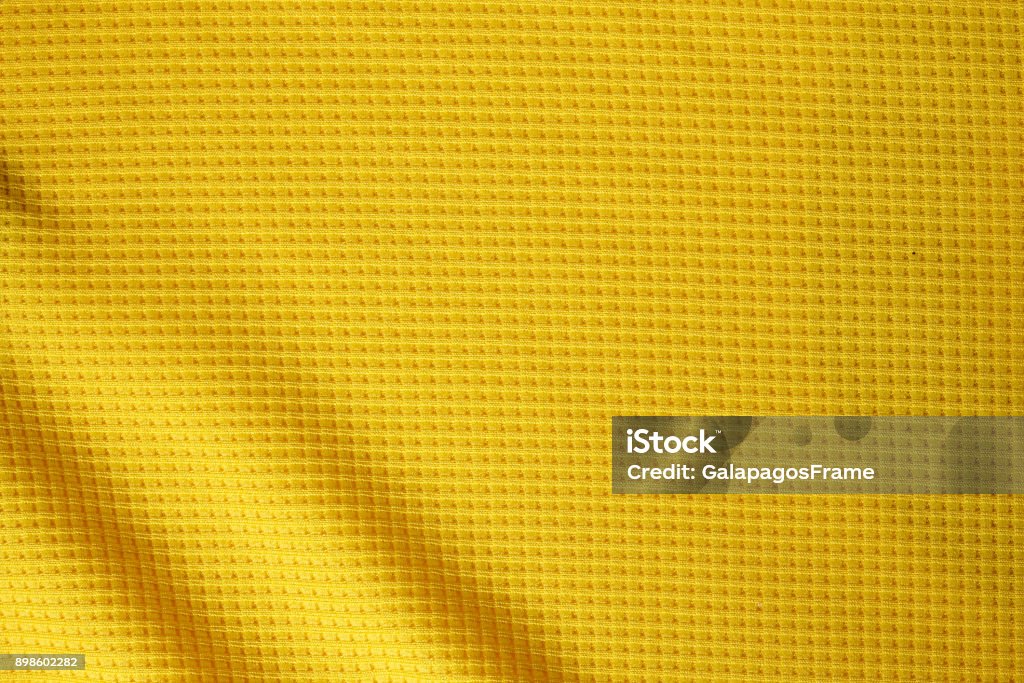 Fundo de textura tecido roupa esporte. Vista superior da superfície do pano têxtil. Camisa de futebol amarelo. Espaço de texto - Foto de stock de Camisa royalty-free