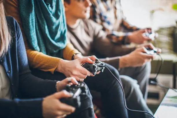 Group of young happy friends playing video games at home.