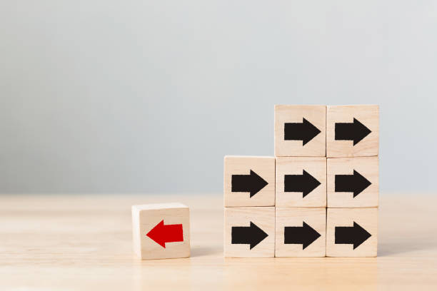 istock Wooden block with red arrow facing the opposite direction black arrows, Unique, think different, individual and standing out from the crowd concept 898633338