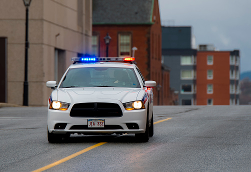 Saint John, New Brunswick, Canada - November 26, 2017: A police car with its red and blue lights on travels at high speed down the center of a city street.