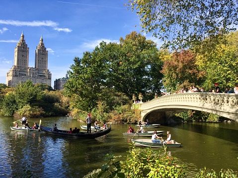 Manhattan, New York, October 22, 2017: people on boats and Bow bridge at Central Park in autumn