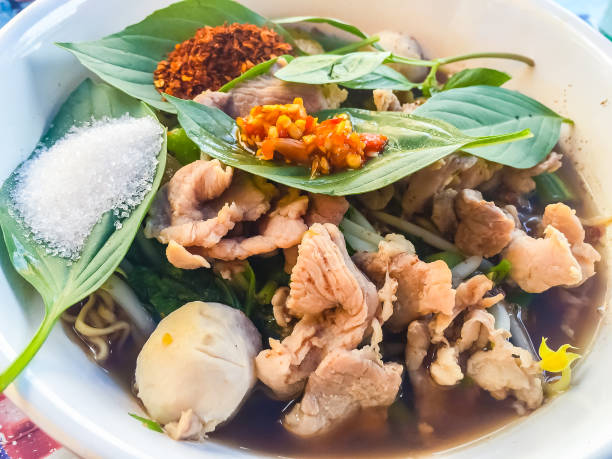 Popular street food in Thailand, Spicy pork noodle that consisted of pork ball, pork meat, basil or thyme, bean sprouts, morning glory, noodle and creamy soup which favouring with sugar, fish sauce, chilli and vinegar marinade comida callejera de popular en tailandia, tallarines del cerdo que consisten en bolas de carne de cerdo, carne de cerdo, albahaca o tomillo, brotes de soja, gloria de mañana, tallarines y sopa cremosa marinada que favorecer con el azúcar, salsa de pescado, ají y vinagre