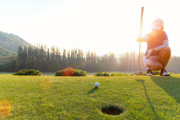 jogador de golfe mulher asiática agachando e estudo o verde antes de colocar o tiro.  conceito de estilo de vida - golf women female concentration - fotografias e filmes do acervo