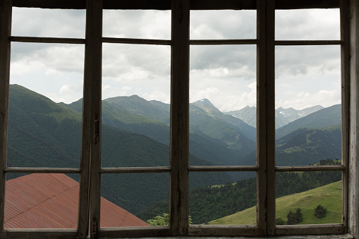 view of the mountains through a glassless window in the remote mountain village of Bochorna in the Tusheti region of Georgia