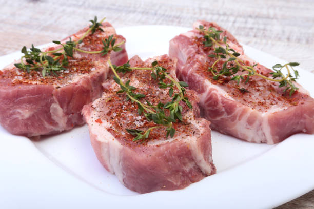 istock Raw pork chops, spices and rosemary on cutting board. Ready for cooking. 898675476