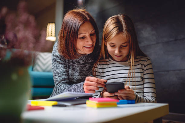 madre e figlia usano lo smartphone - child digital tablet mother teaching foto e immagini stock
