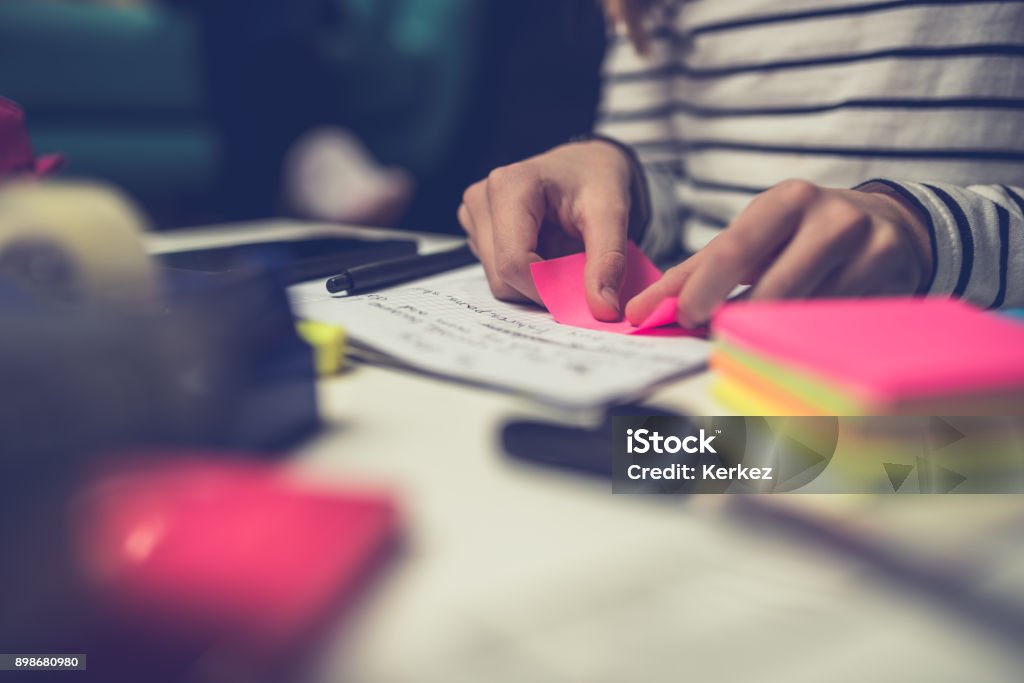 Girl peeling off sticky notes Girl doing homework late at night and peeling off sticky notes Adhesive Note Stock Photo