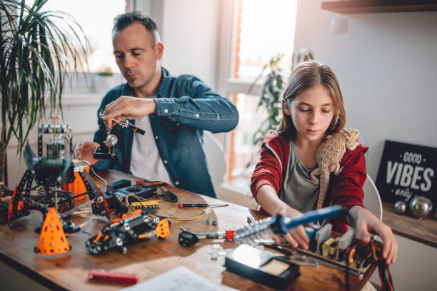 Father and daughter building robot Father and daughter sitting by the wooden table and building robot at home  as a school science project exotic pets photos stock pictures, royalty-free photos & images