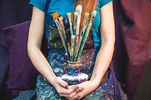 Female artist holding a bunch of brushes. Creativity and imagination concept