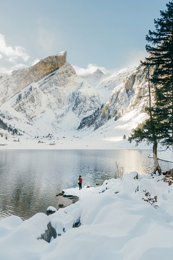Young Caucasian woman standing  near  the lake in Switzerland in winter