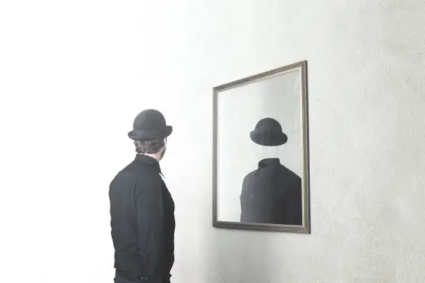 Photo of identity absence surreal concept; man in front of mirror reflecting himself without face