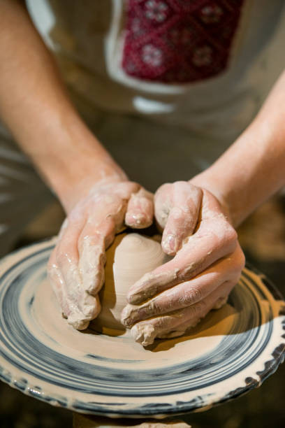 istock guy molds a jug from a clay on a potter's wheel 898712712