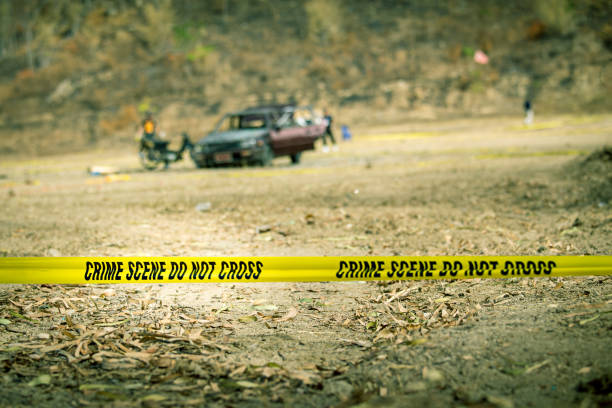 police line tape with blurred law enforcement and wrecked car background stock photo