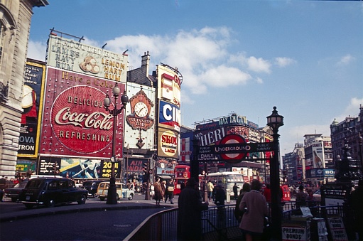 London, England, UK, 1969. The famous Piccadilly Circus in the London City. You can see the advertising signs and illuminated signs, which were attached to the house facades. Furthermore:  traffic. Double decker buses, cars and pedestrians.