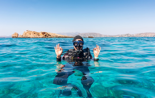Female scuba diver gives the OK sign in turquoise waters