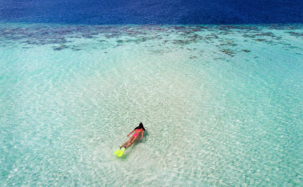 istock Woman snorkeling towards a coral reef 898732020