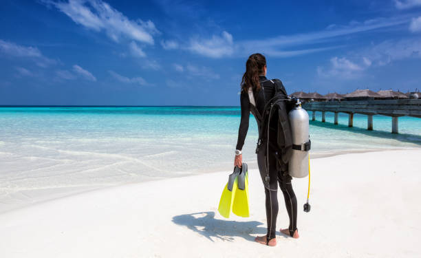 istock Female scuba diver with diving equipment on the beach 898732982