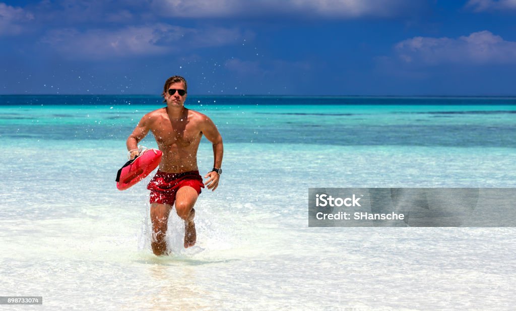 Lifeguard running in turquoise waters Male lifeguard running in turquoise waters in the Maldives Lifeguard Stock Photo