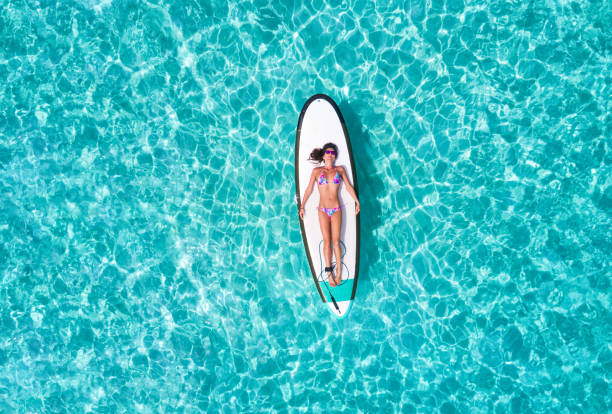 istock Woman in bikini is sunbathing on a surfboard 898733532