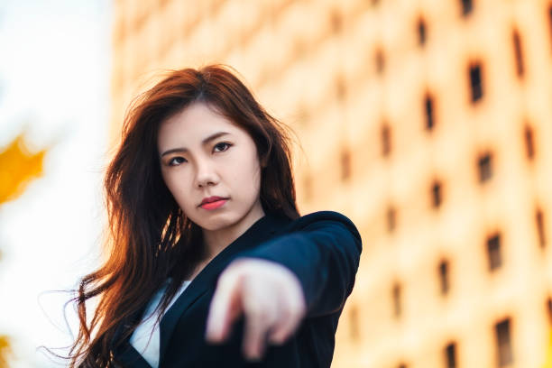 An angry Japanese businesswoman is pointing her finger for judgement.