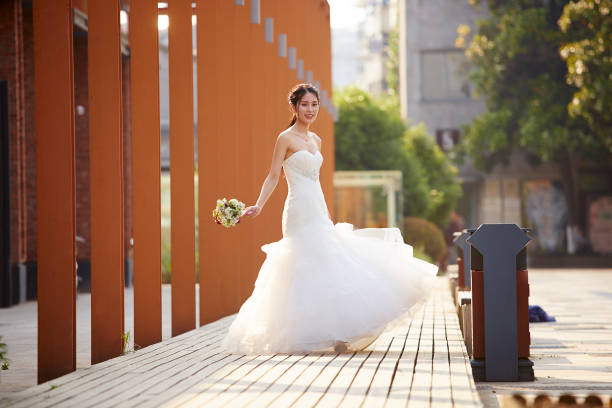 outdoor portrait of young and beautiful asian bride with bouquet in hand.
