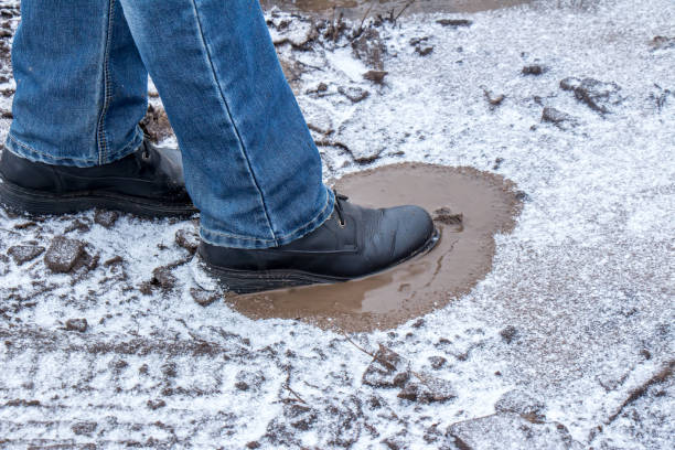 istock A man steps into a frozen puddle with mud 898748700