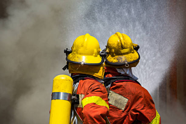 two firefighters fire fighting surround with dark smoke two firefighters water spray by fire hose surround with dark smoke soaked suit stock pictures, royalty-free photos & images
