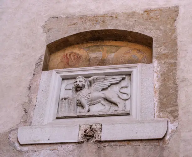 Photo of Stone bas-relief of the Venetian lion on one of the houses of Canegliano. The lion of St. Mark is a symbol of the city of Venice, and one of the elements of the flag of the Italian fleet.