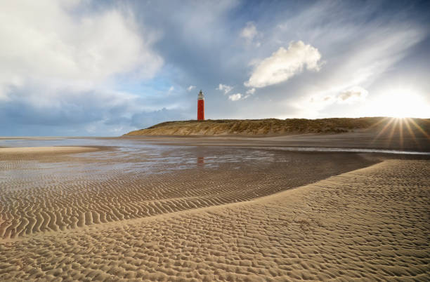 istock morning sunshine over sand beach and red lighthouse 898761336
