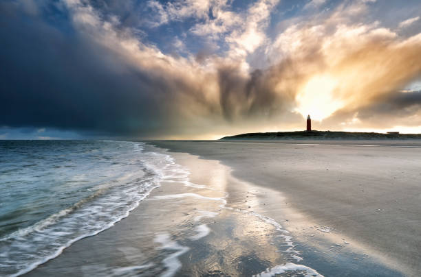 dramatic sunrise sky over lighthouse on beach - storm lighthouse cloudscape sea imagens e fotografias de stock