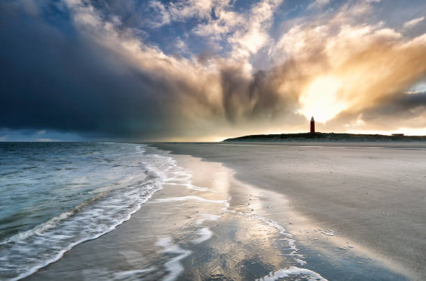 драматические восхода неба над маяком на пляже - storm lighthouse cloudscape sea стоковые фото и изображения