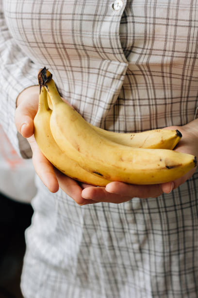 istock Woman holding three ripe bananas in arms 898765080