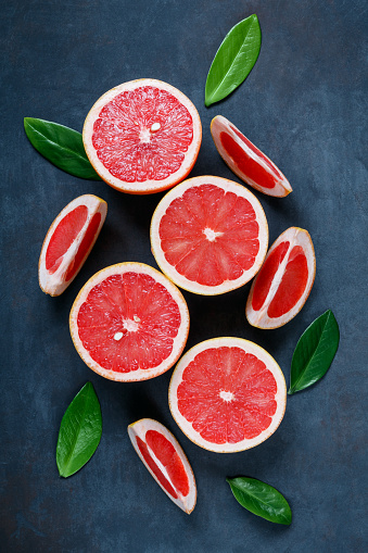 Fresh and ripe sliced citrus fruits. Slices of orange, tangerine, lemon and grapefruit in a wooden plate on a dark background. Fresh and colorful concept
