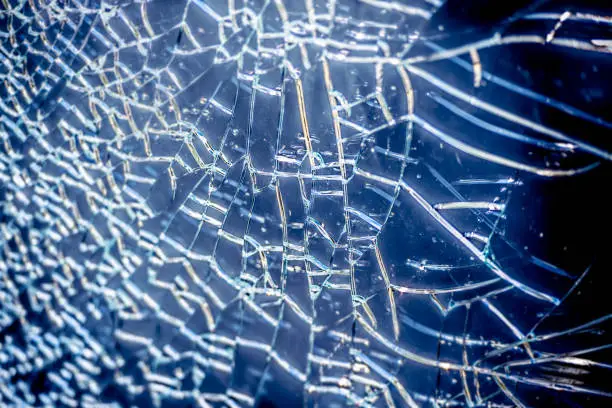 Broken glass surface with cracks. Blue tint and white lines.