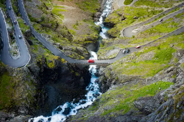 Photo of Trollstigen mountain road. Bridge over river with waterfall. Cars on serpentine. Auto travel in Norway, Europe, Scandinavia