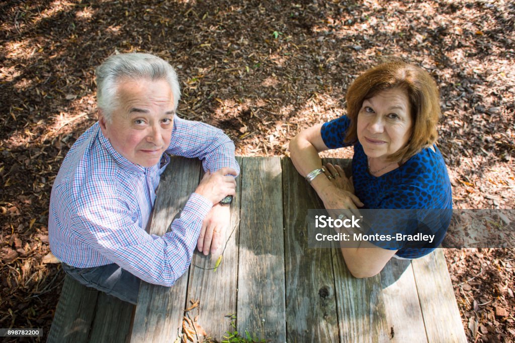 Abuelos, the Latino Grandparents A white Spanish-Latino couple sitting at a picnic table with Autumn foliage covering the ground. Greek Culture Stock Photo