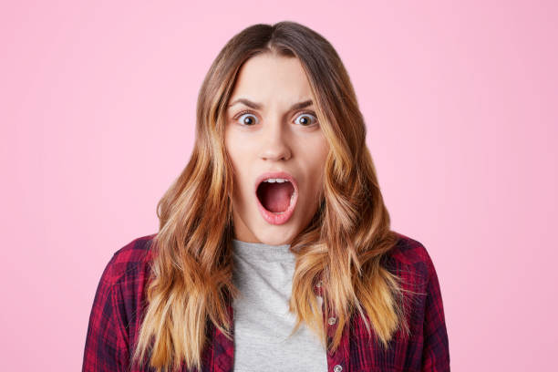 istock Shocked stupefied female student, opens mouth widely, being surprised to know that tomorrow is final exam, wears checkered shirt, isolated over pink background. Negative human emotions concept 898794146